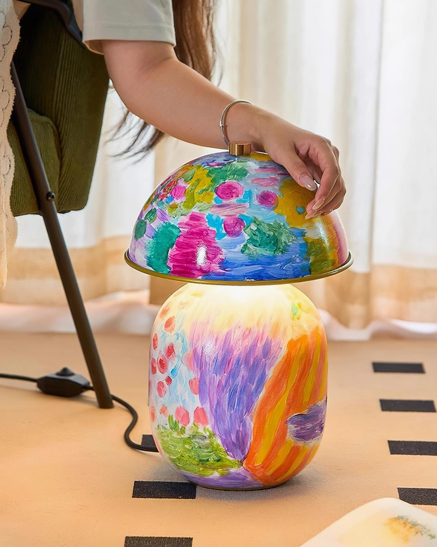 Colorwave artistic table lamp with visible power cord and hand adjusting fabric shade on floor placement