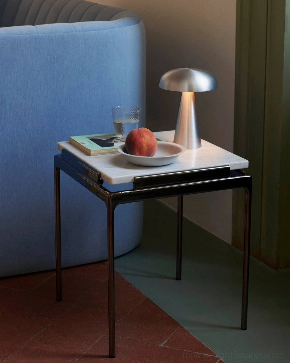 Matte silver Como table lamp on modern living room side table paired with blue sofa and interior design elements