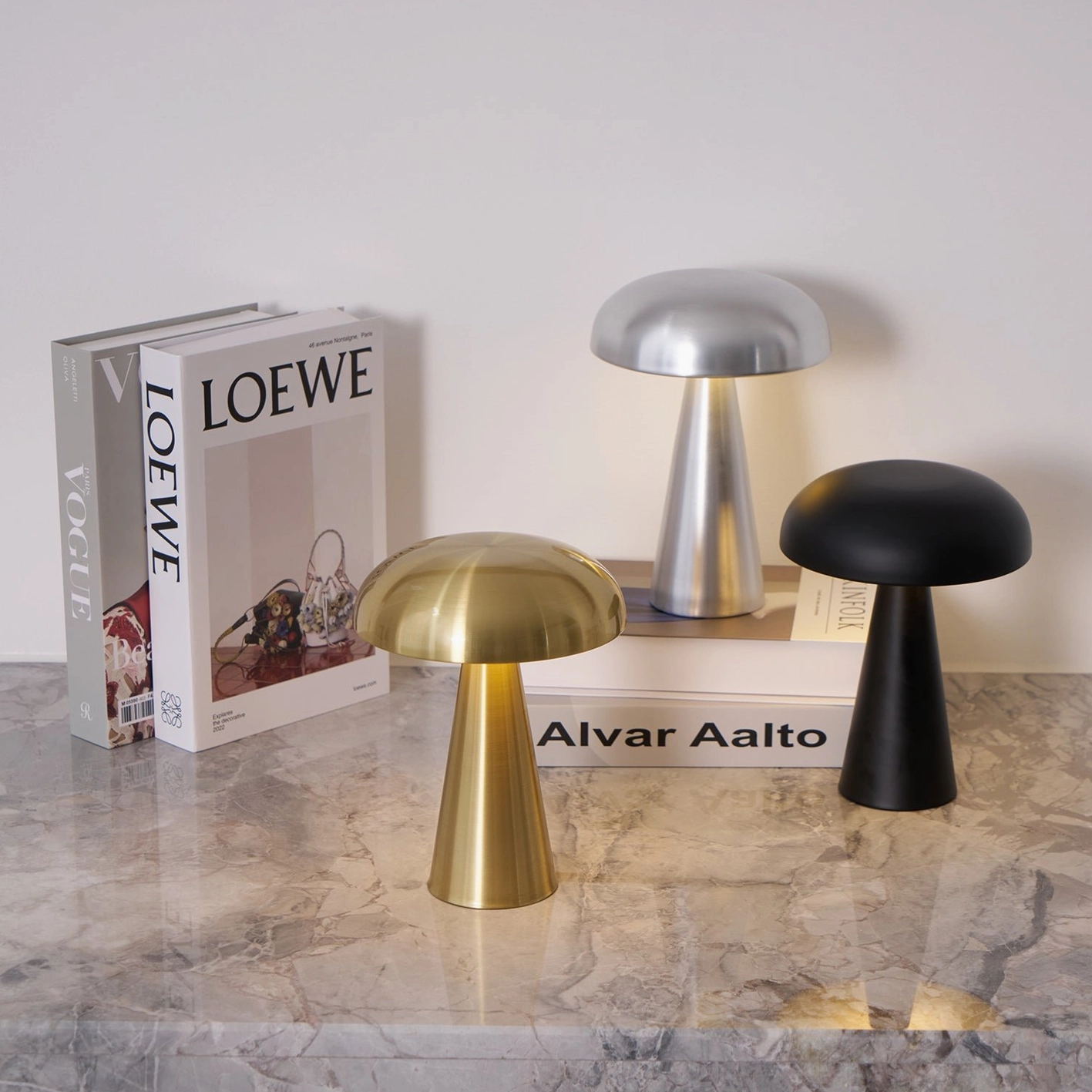 Multiple Como table lamp color options arranged on luxury marble console with design books and decor