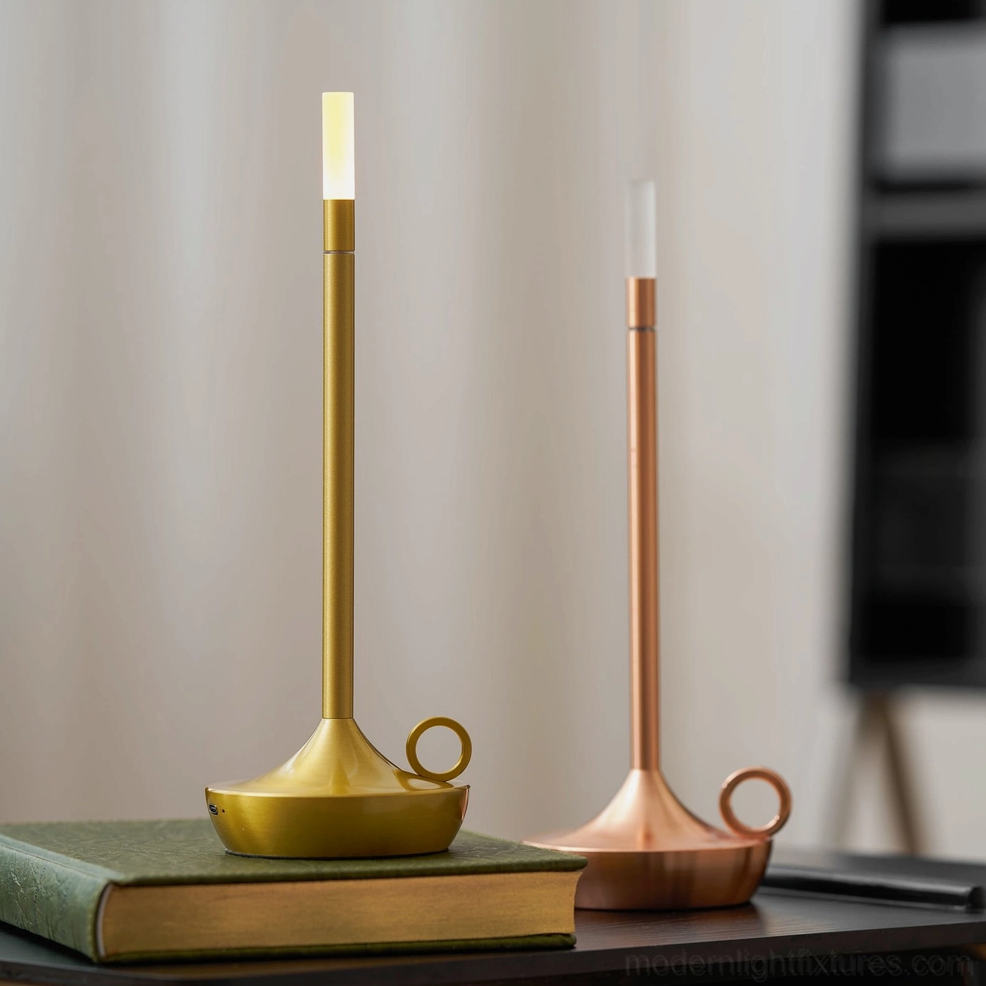 Compact LED candle table lamps in brass gold and rose gold on indoor side table with curtain backdrop, contemporary styling