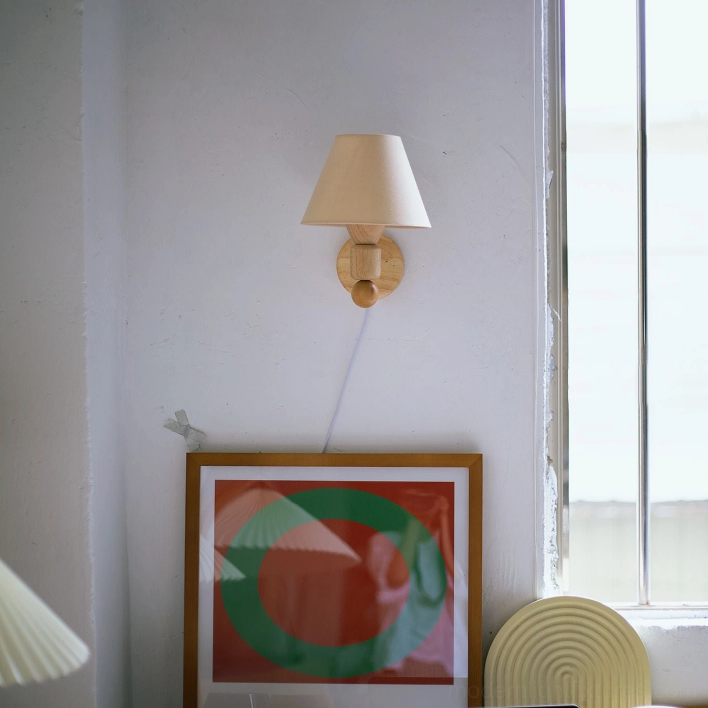 Compact minimalist wall sconce with beige conical shade showing minimal wooden base and warm ambient lighting effect