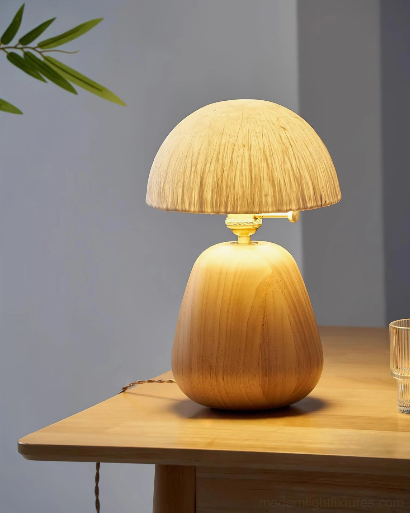 Small oak wood table lamp with fabric power cord on wooden table in studio lighting with grey backdrop