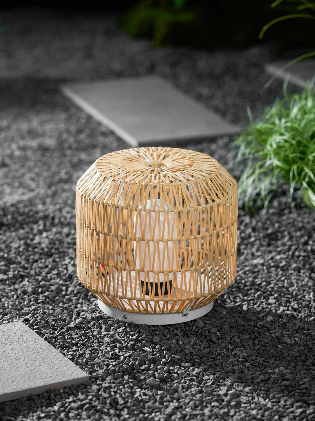 Compact rattan outdoor lamp on small balcony creating intimate cozy ambient lighting