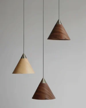 Three Conira pendant lights clustered together with mixed wood grain cone shades suspended from black cords, contemporary Nordic trio lighting installation