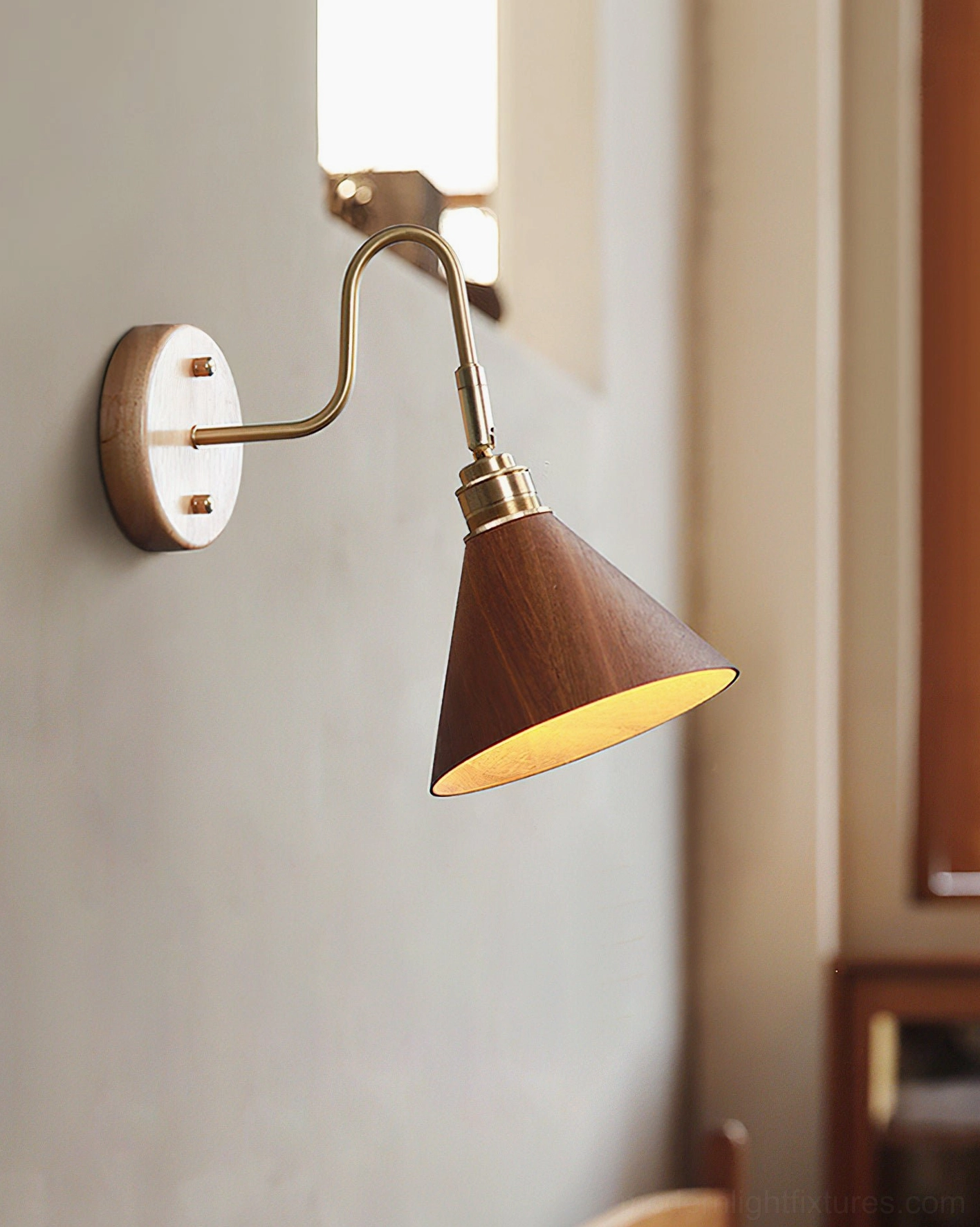 Conira brass wall sconce installed in bedroom providing warm ambient lighting - residential interior