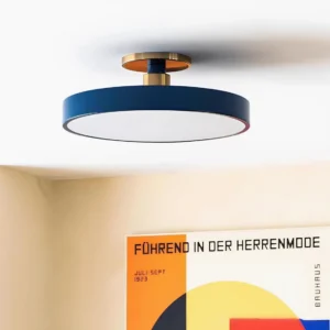 Contemporary semi-flush ceiling light fixture with navy blue disc shade and brass mounting base, angled view