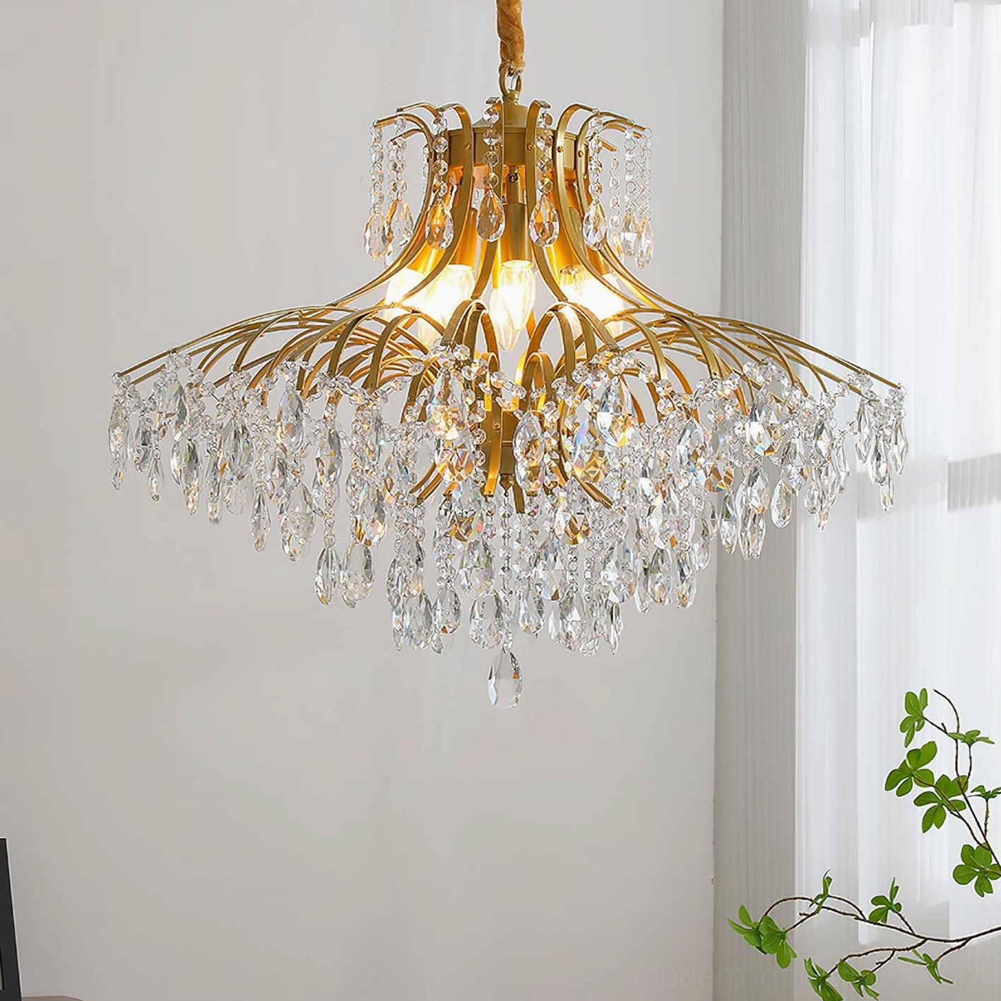 Contemporary gold crystal chandelier creating luminous waterfall effect in elegant home interior