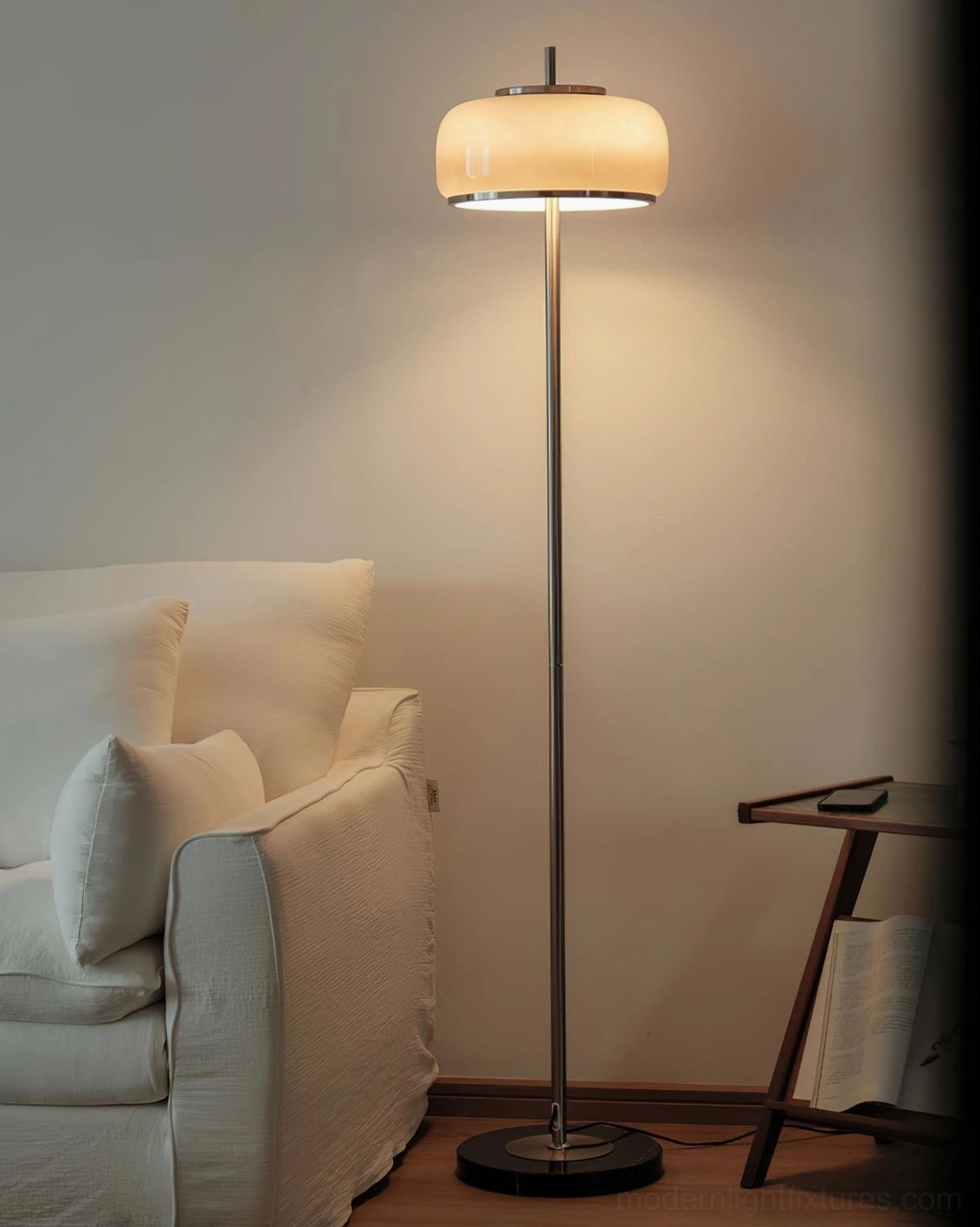 Minimalist floor lamp with beige glass dome and chrome metal stem in contemporary living room with sofa and side table