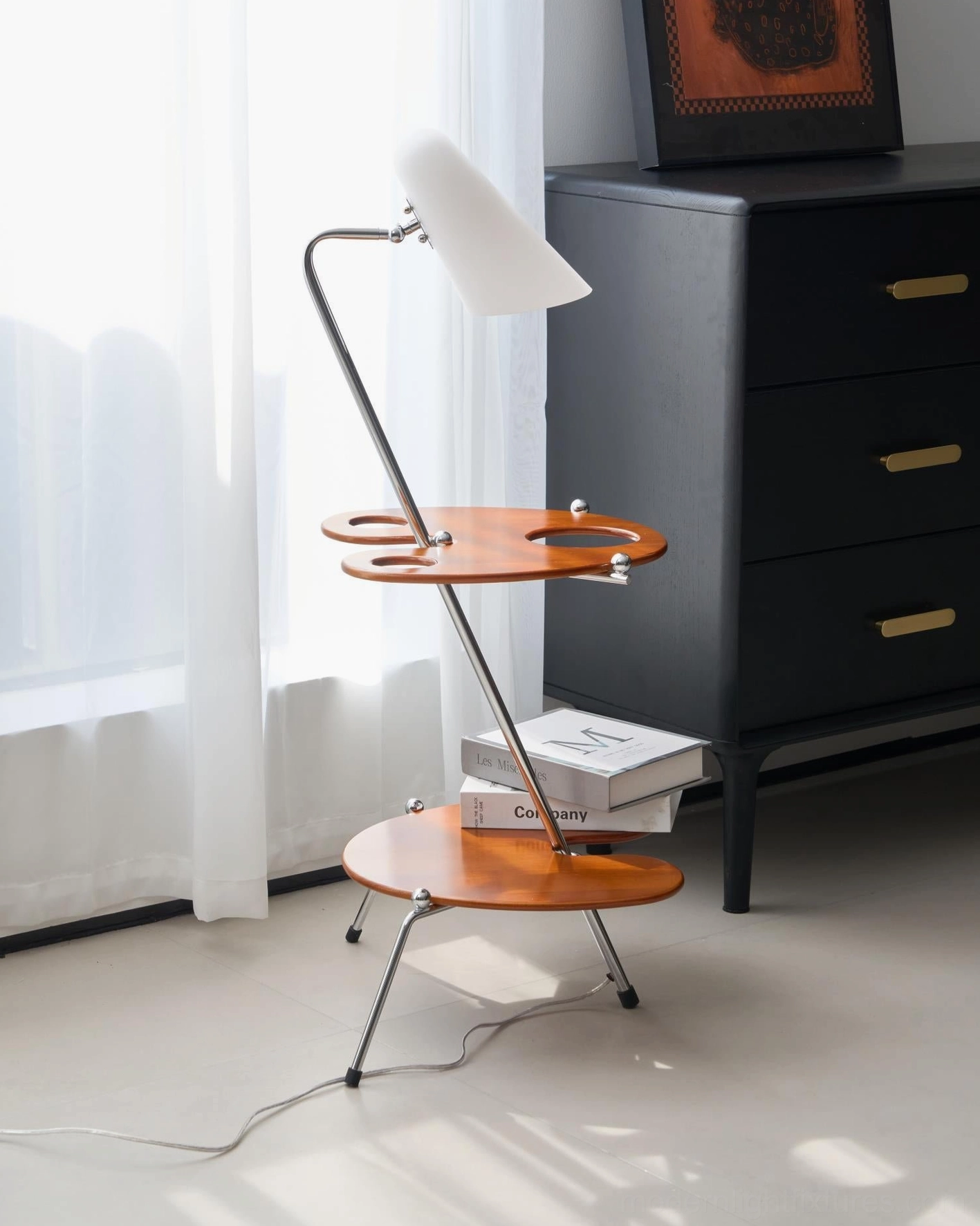 Architectural floor lamp with white conical shade beside black dresser in bright modern bedroom with sheer curtains