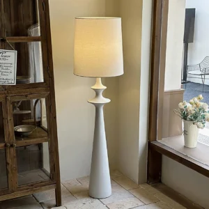 Minimalist floor lamp positioned in vintage home corner with wooden cabinet and neutral interior
