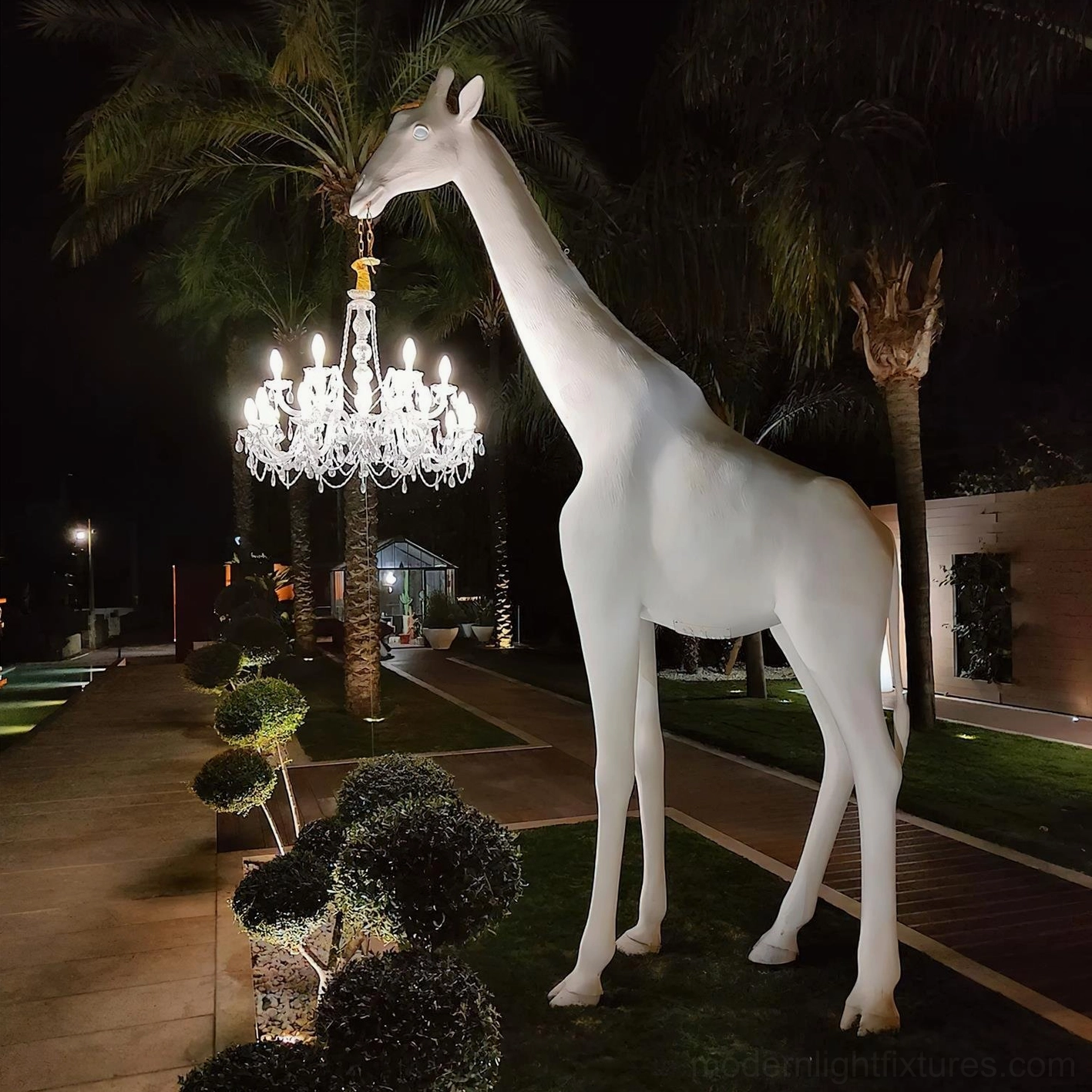 Contemporary giraffe sculpture floor lamp creating dramatic focal point with illuminated crystal chandelier