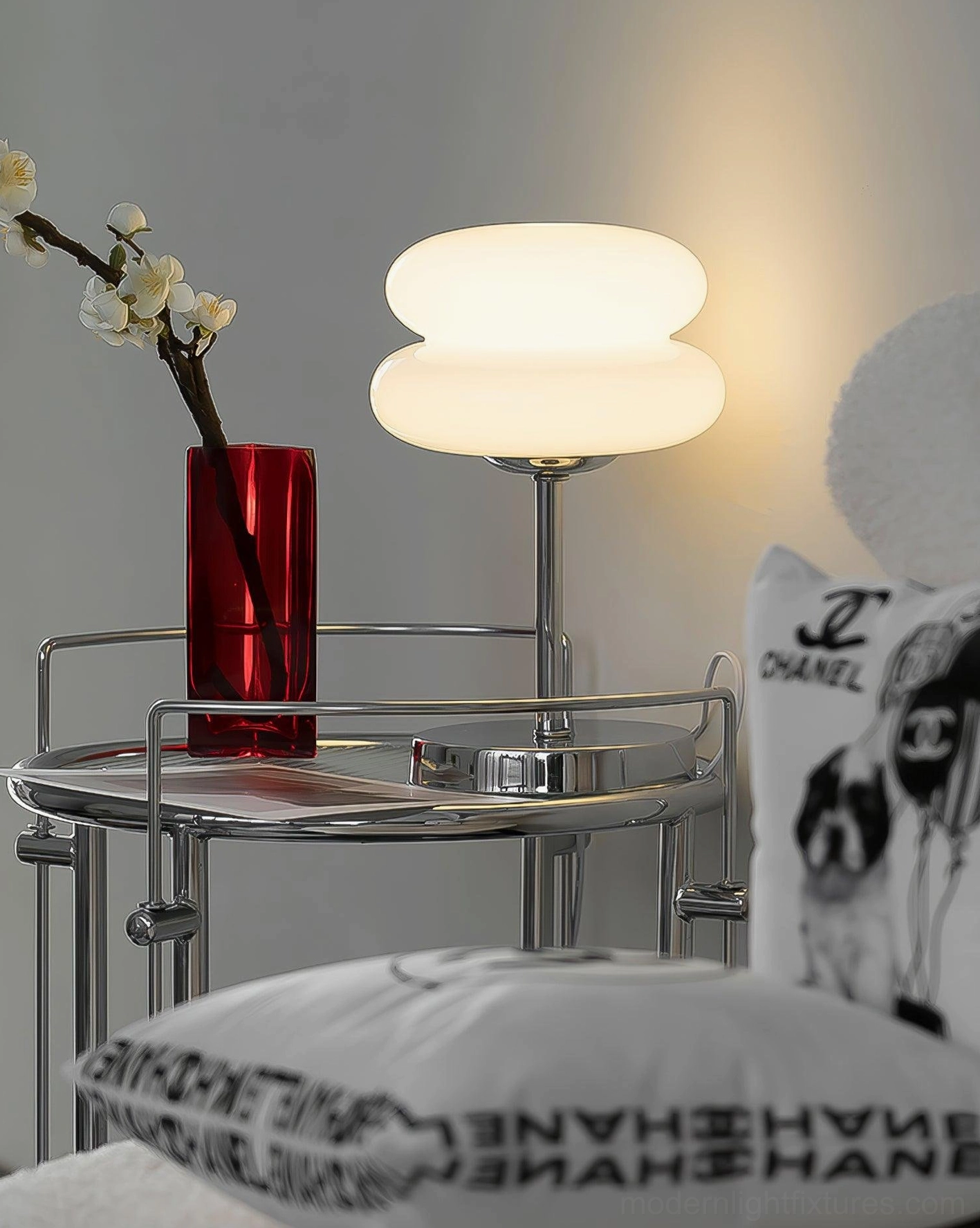 Full view of minimalist glass table lamp with chrome metal base on neutral background