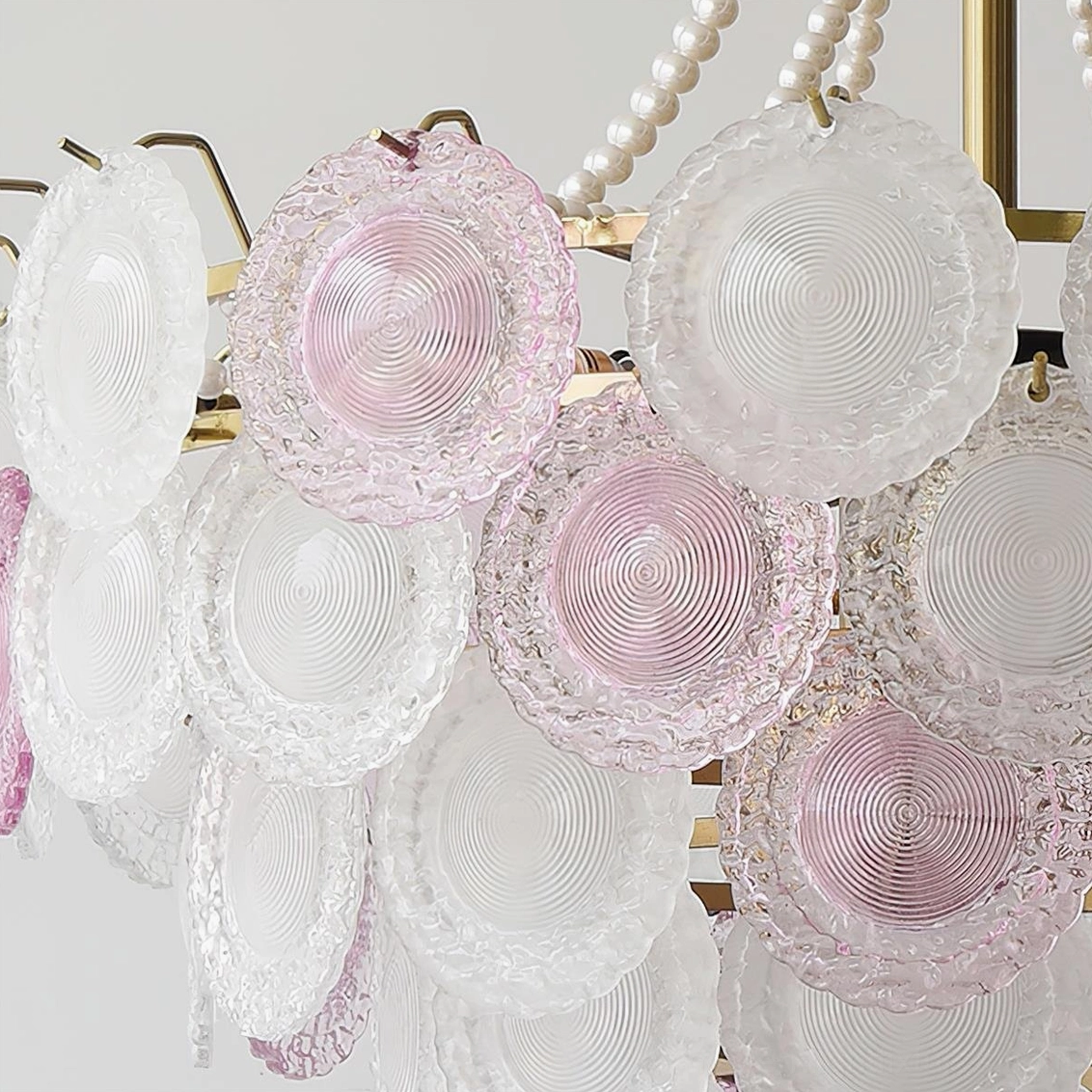 Modern tiered chandelier showing pink frosted glass shades and brass metalwork in contemporary interior setting