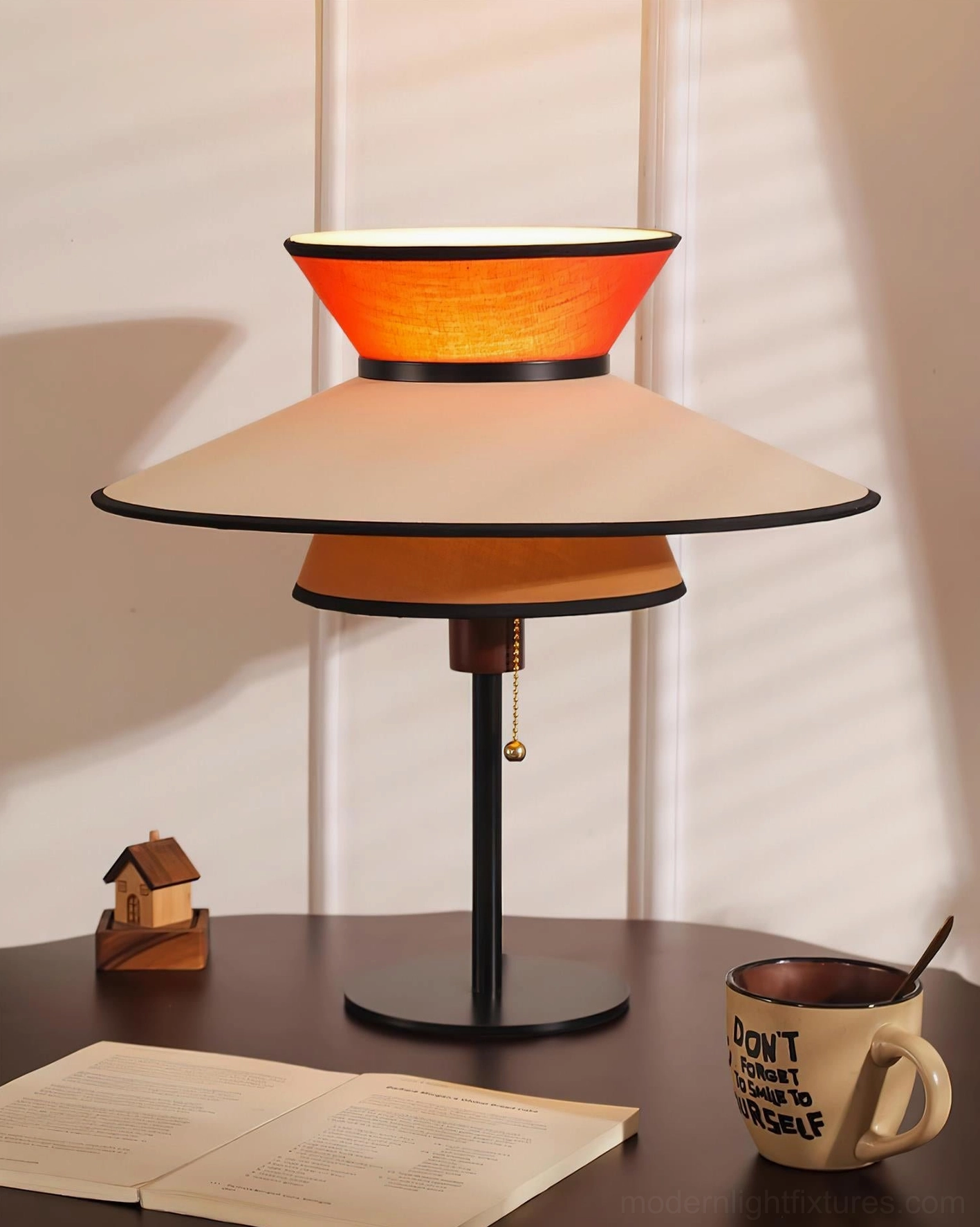 Contemporary layered table lamp with warm illumination on dining room side table with open book and coffee mug styling