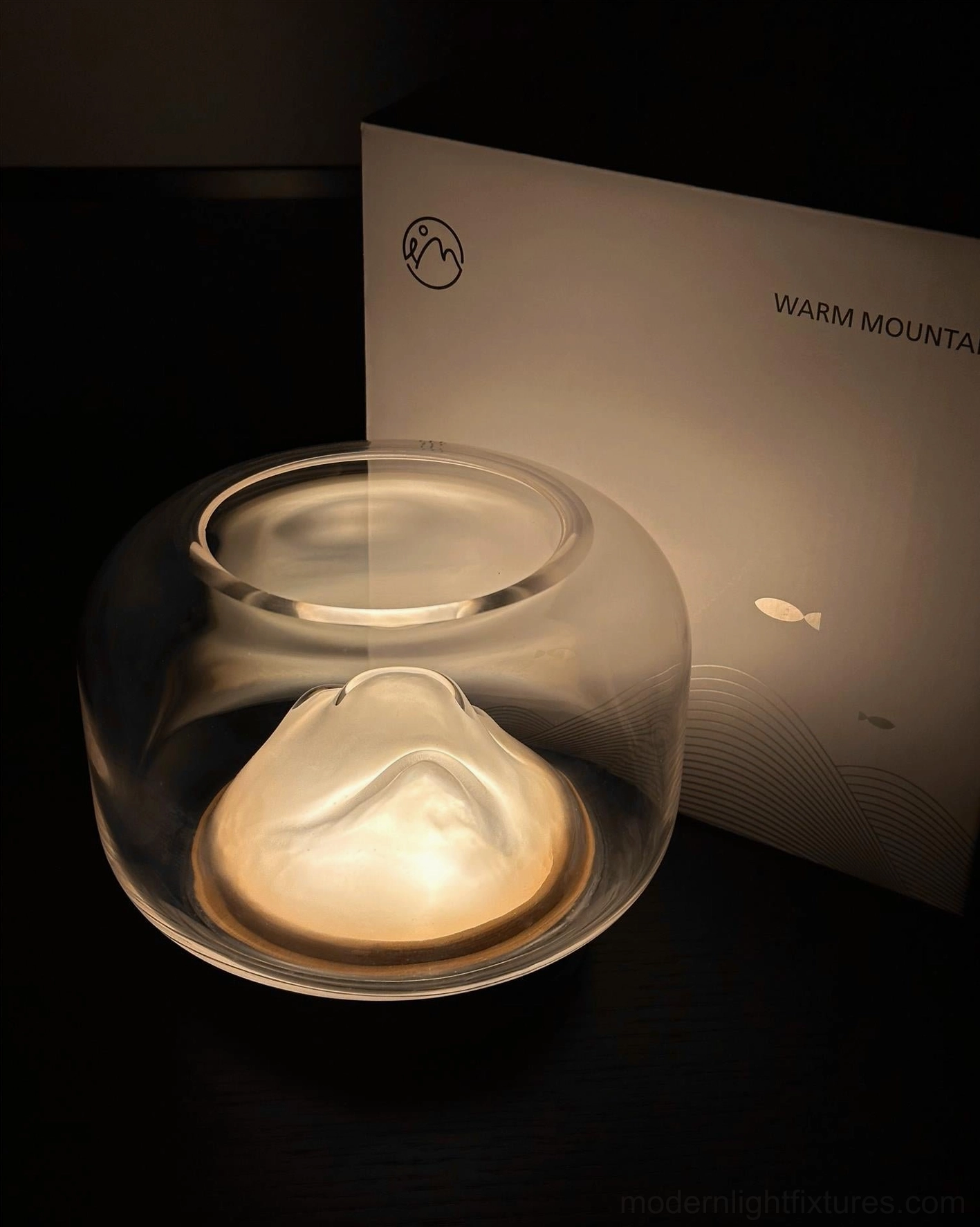 Contemporary mountain table lamp low angle view, illuminated mountain interior, wooden base on dark tabletop