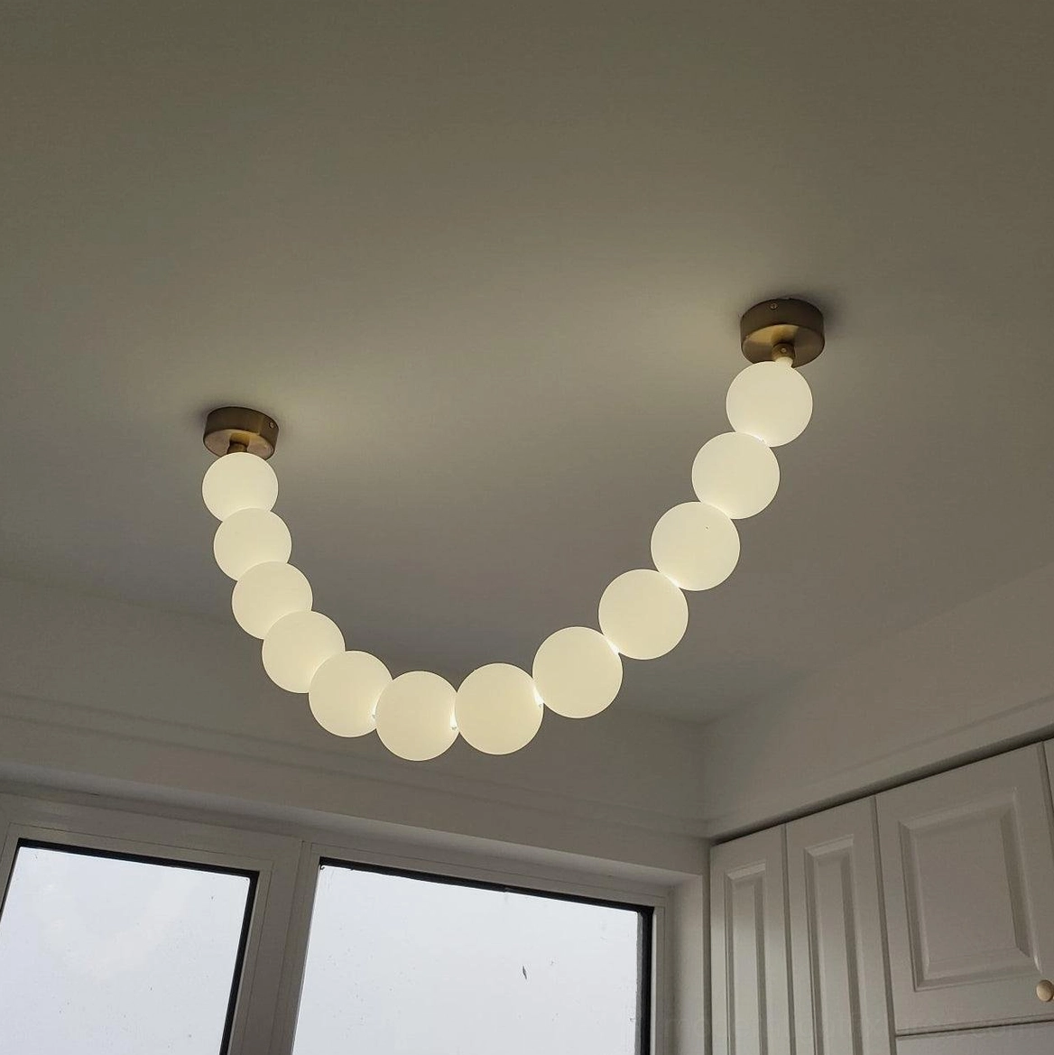 Contemporary pearl string chandelier with clear acrylic spheres and brass metal framework
