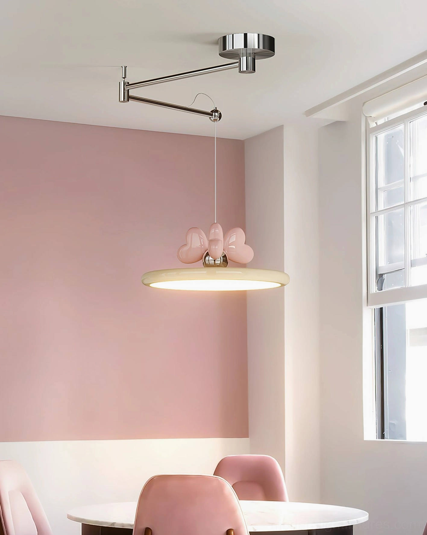 Modern pendant light in dining space with pink accent wall, window, and coordinating pink dining chairs