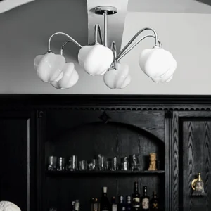 6-head sculptural chandelier installed in contemporary home bar, low-angle upward view showing warm glowing acrylic shades and curved chrome arms
