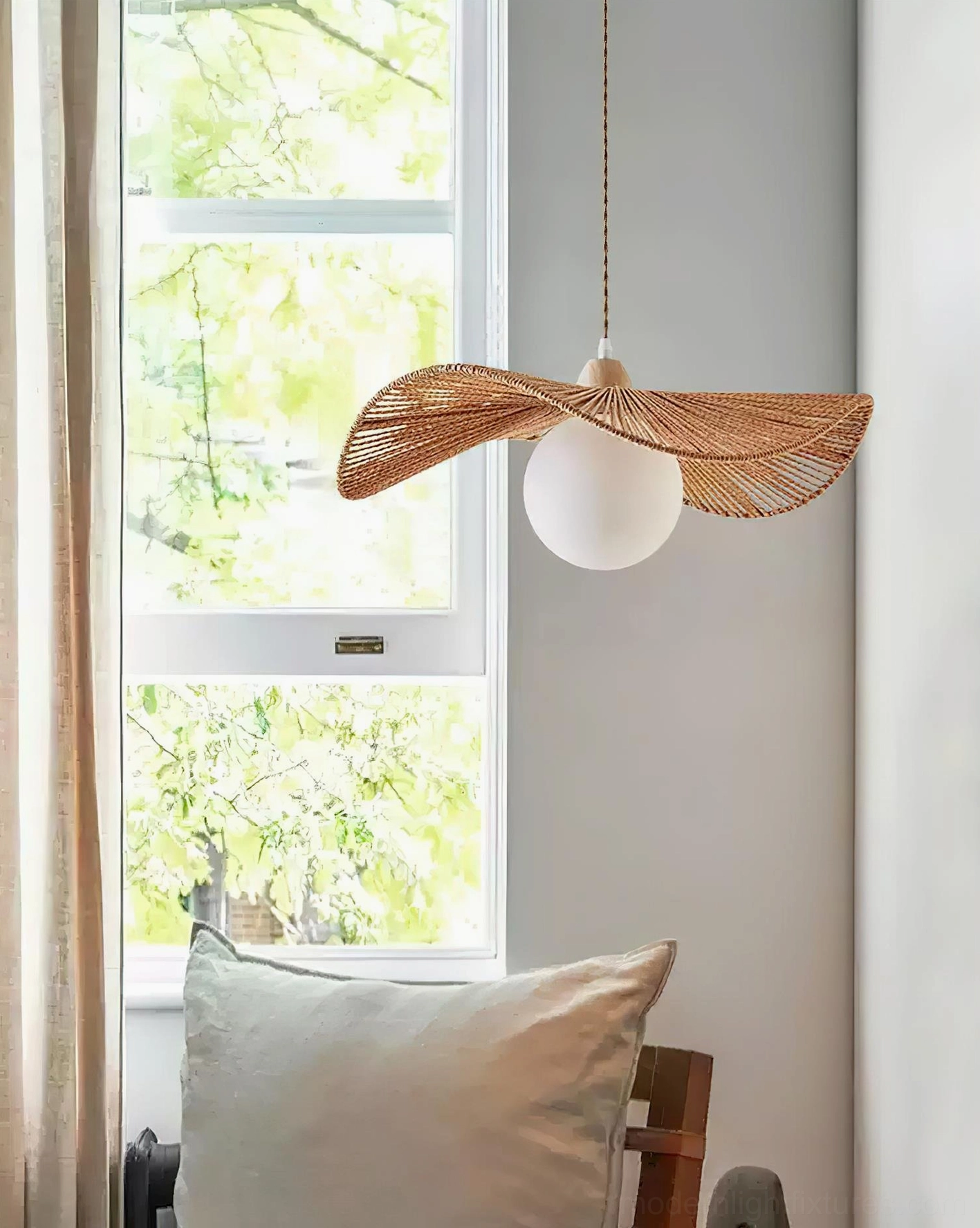 Pair of contemporary rattan pendant lamps by window with natural daylight and linen cushion styling