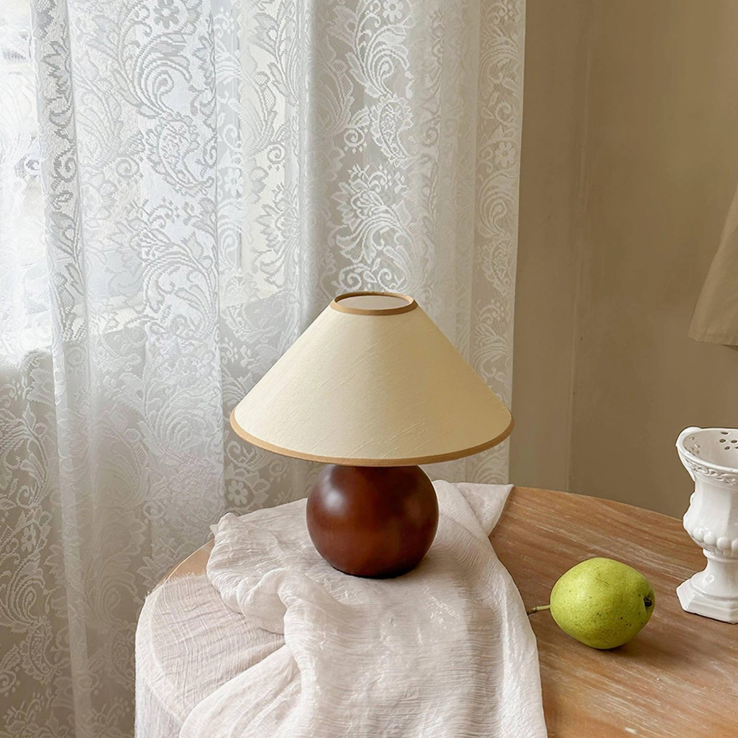 Contemporary table lamp with wooden spherical base and tapered shade in home setting