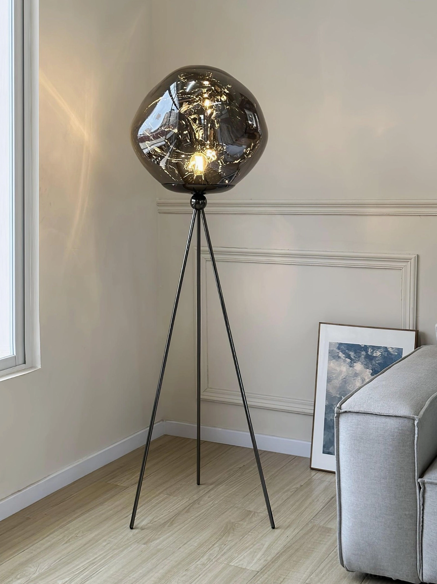 Contemporary tripod floor lamp emphasizing unique molten lava glass texture and warm ambient illumination