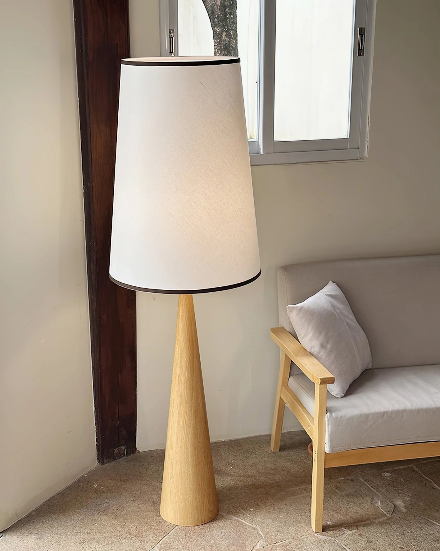 Natural oak wood floor lamp beside contemporary sofa and window in minimalist living room setting