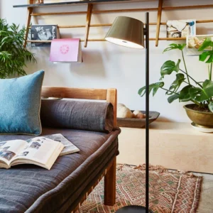 Bronze Contra tapered floor lamp in bohemian living room with daybed and wooden wall shelving