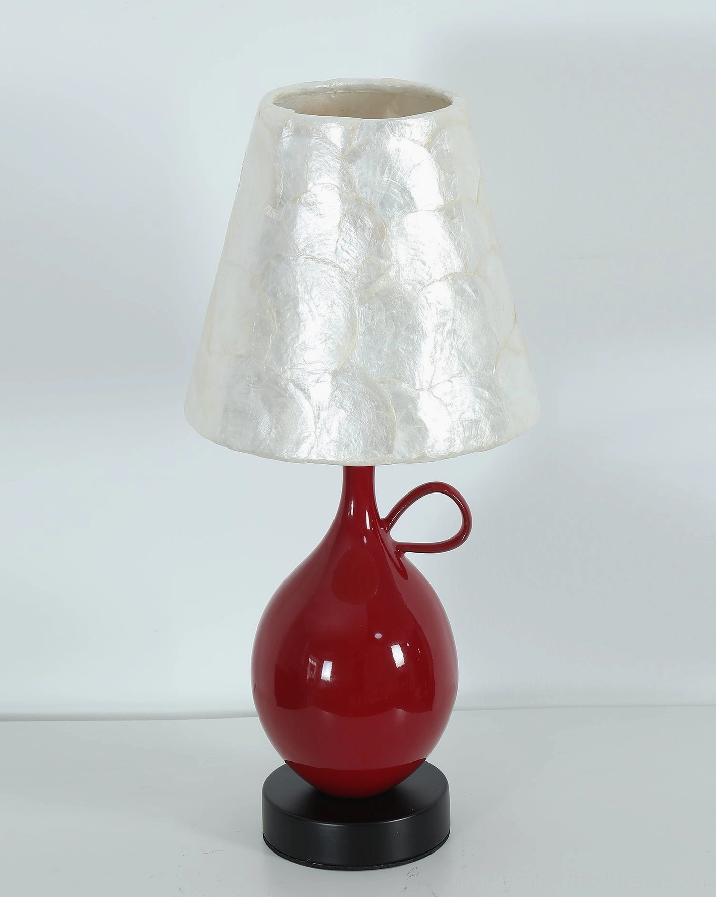 Coravie table lamp lit view showing warm pearlescent glow through capiz shell tiles creating soft ambient light