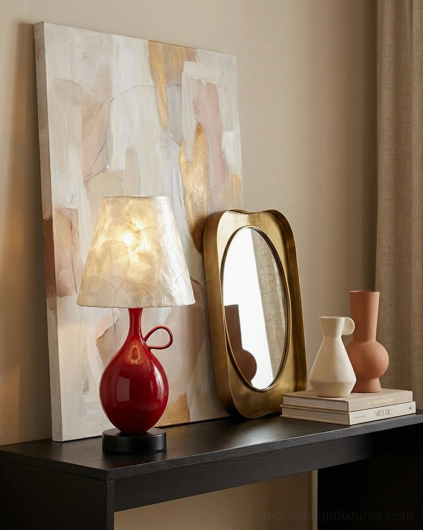 Coravie red ceramic table lamp on dark wood console table with vanity mirrors and abstract artwork in decorative console corner