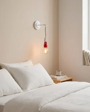 Cordelle wall sconce installed beside bedroom headboard providing warm ambient reading nook light with minimalist décor