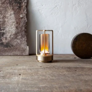 Cordless table lamp with warm ambient light in modern interior setting, oblique side perspective with textured background