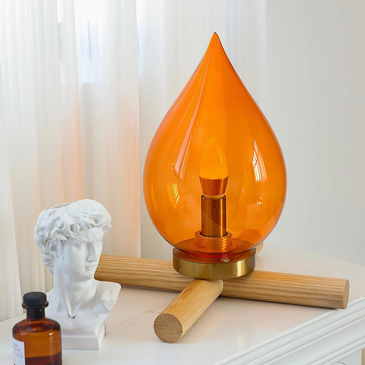Amber glass cordless table lamp on bedroom dresser with decorative accents and sheer curtains