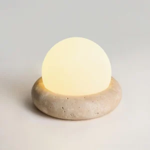 Overhead top view of cordless travertine table lamp showing warm glow diffusion through frosted acrylic sphere