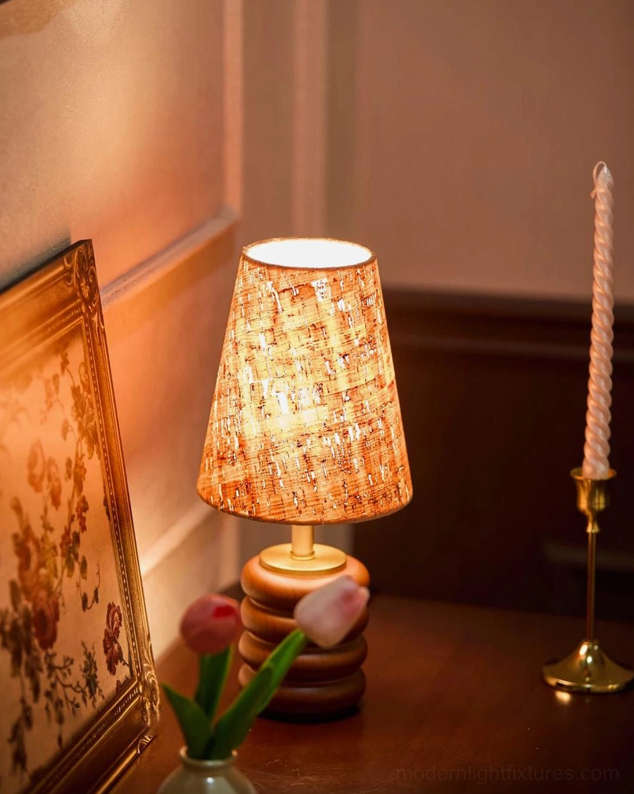 Warm walnut table lamp with cork shade paired with framed artwork and tulip vase on wooden table