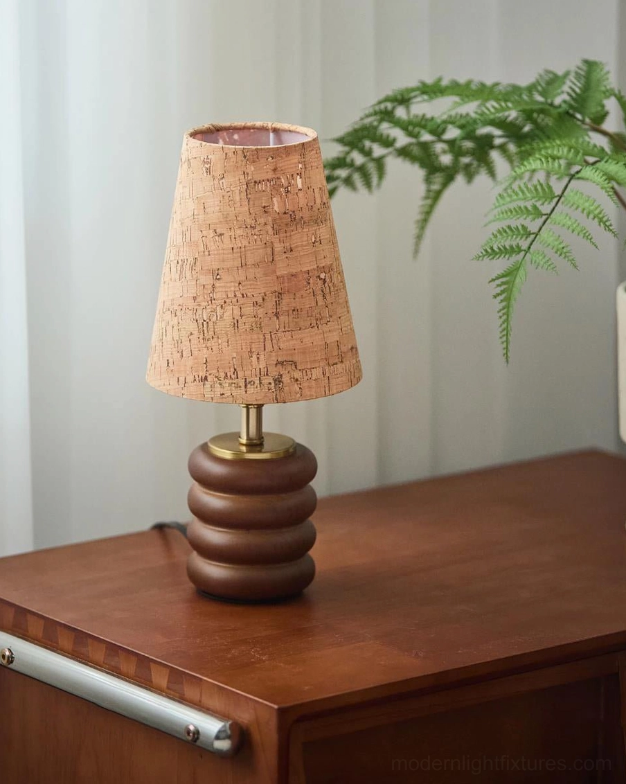 Warm 3000K table lamp with natural cork shade and walnut base on wooden cabinet with green plant backdrop