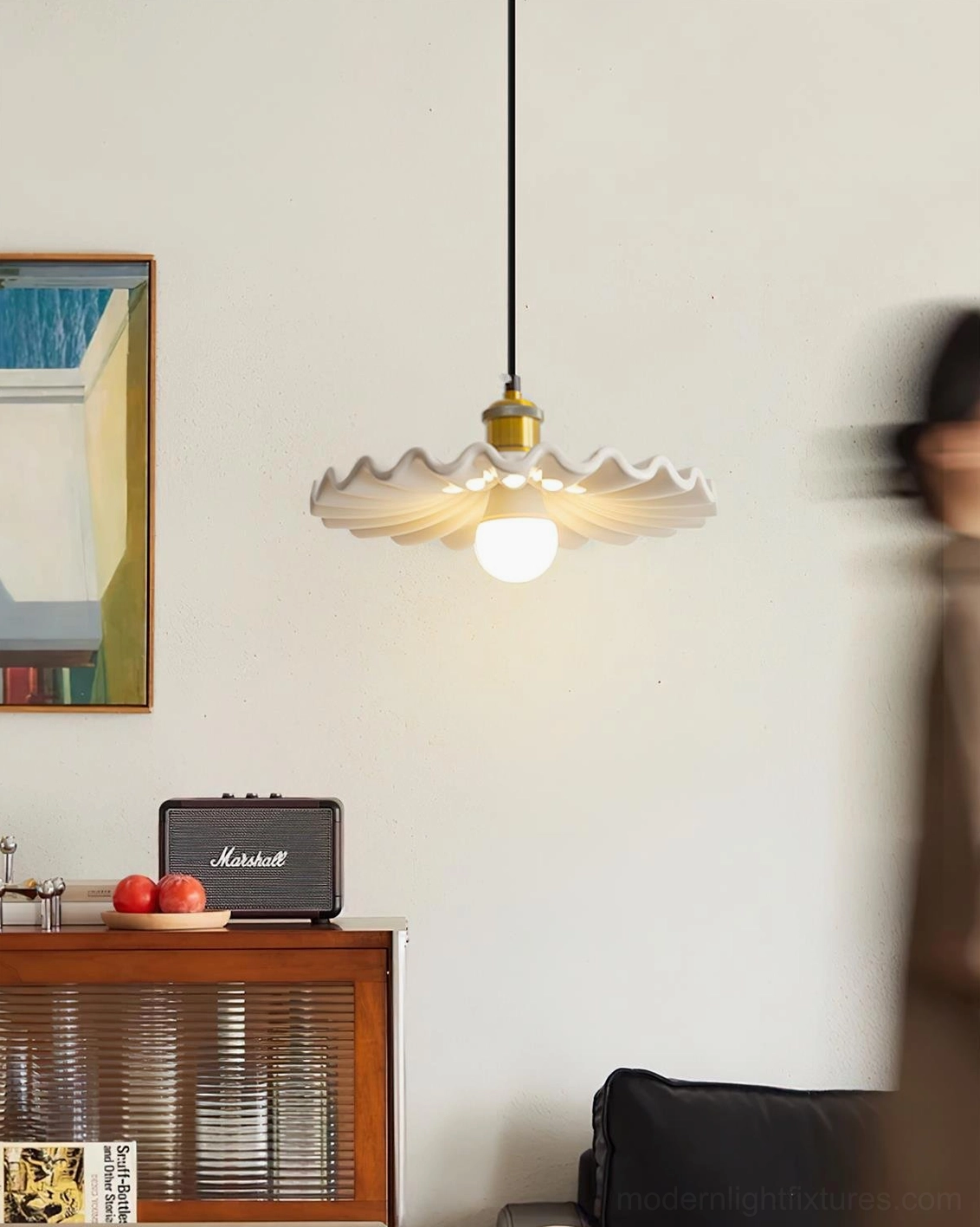 Corolla ceramic pendant light installed in vintage living room with lit exposed bulb and warm brass accents