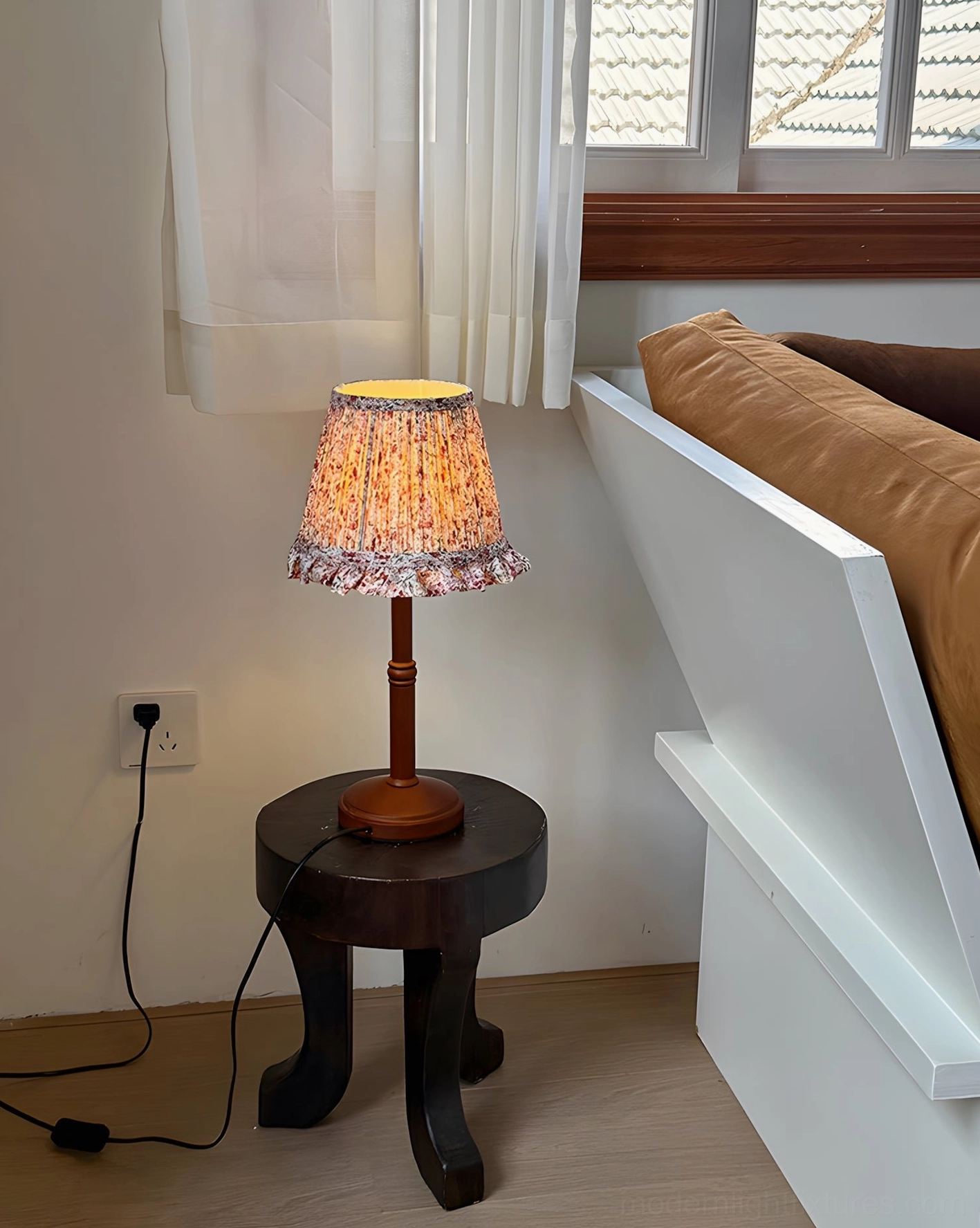 Cottage table lamp on dark wood side table by window bench with power cord connected