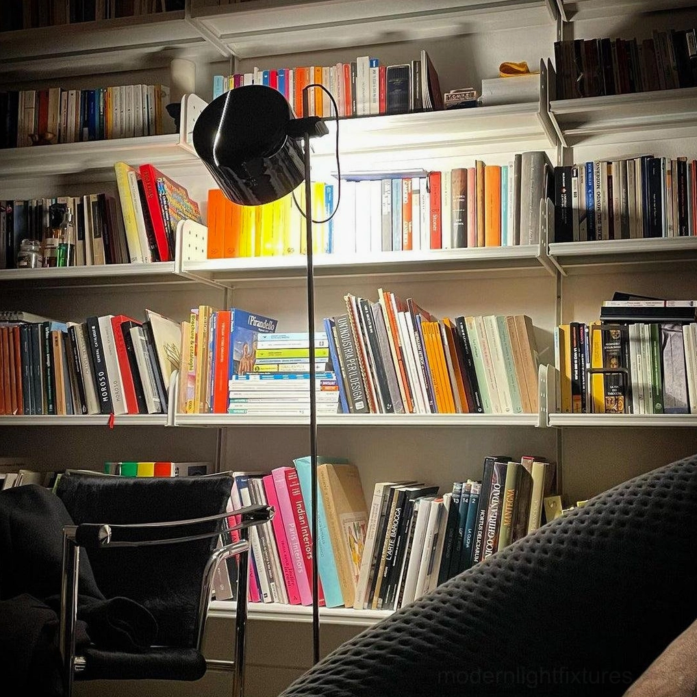 Modern adjustable floor lamp with black matte shade and articulated arm in home library with bookshelves