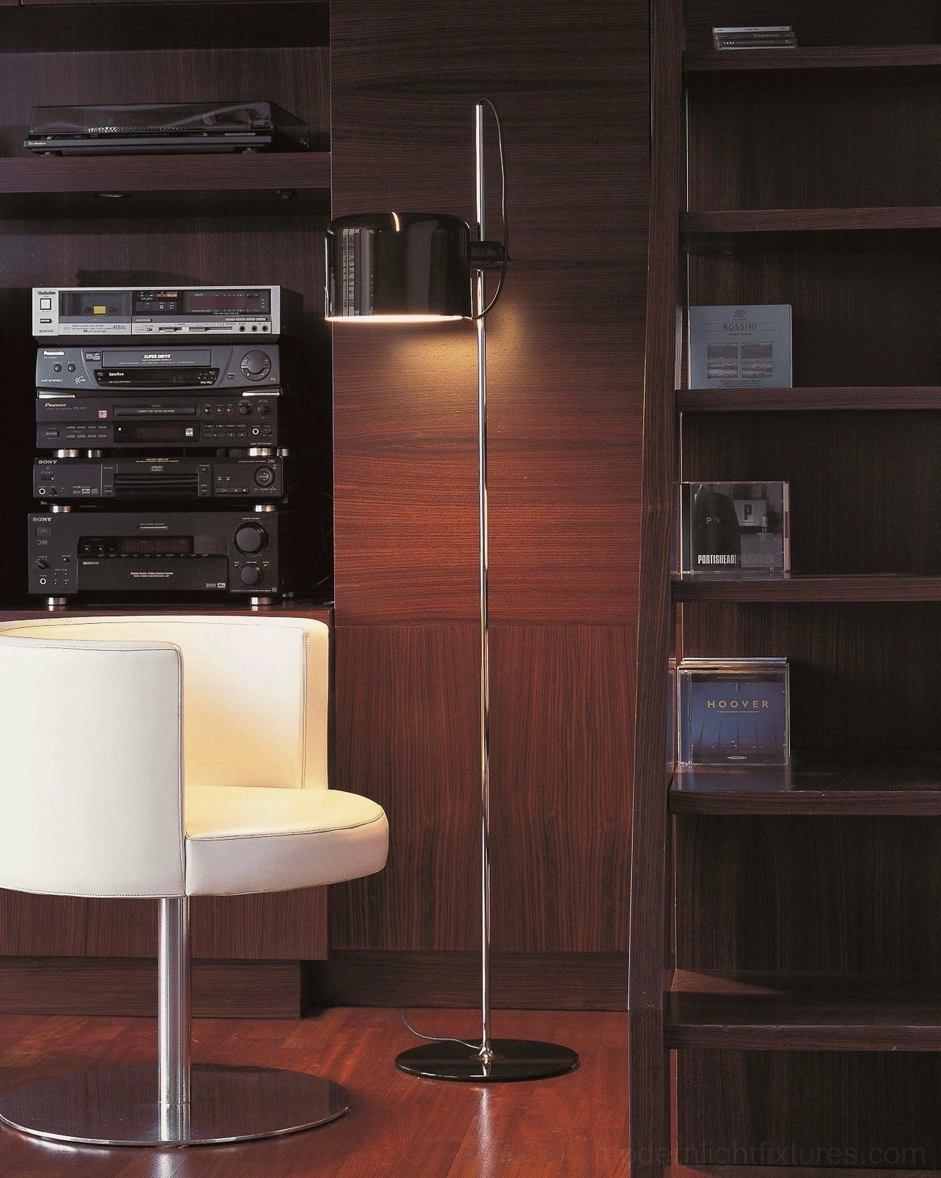 Minimalist adjustable floor lamp with silver pole and black shade in home studio with wooden bookshelves
