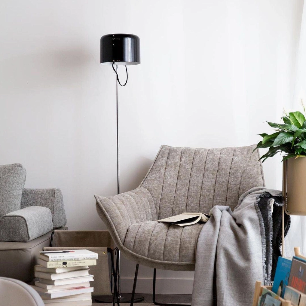 Coupé black cylindrical shade floor lamp in cozy reading corner with grey tufted armchair