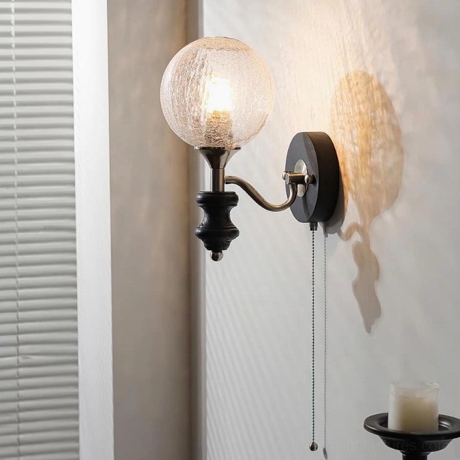 Cracked textured glass globe wall sconce with black metal hardware and pull-chain switch