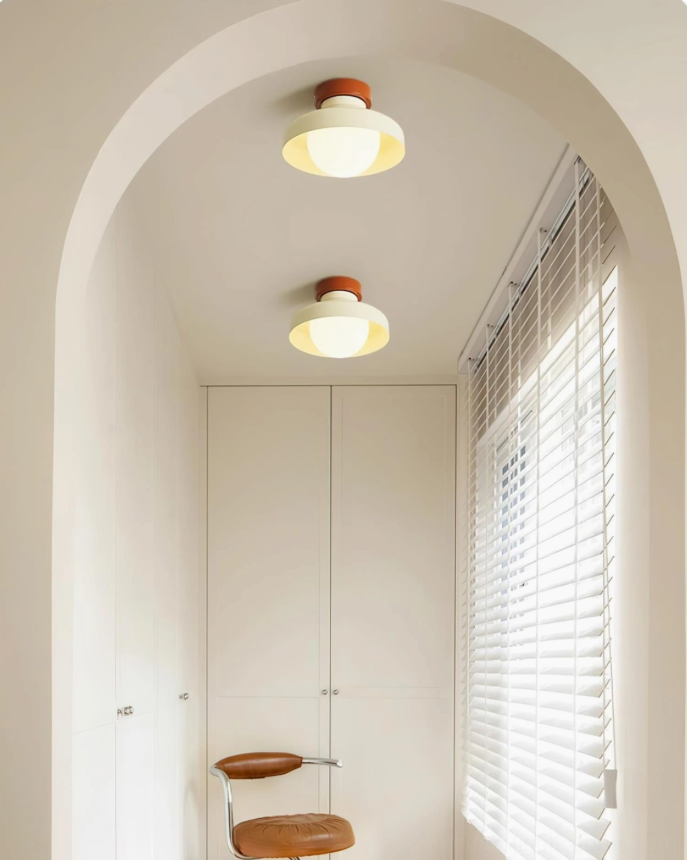 Cream white modern flush mount ceiling light in minimalist entryway with coat rack and bench seating, soft lighting