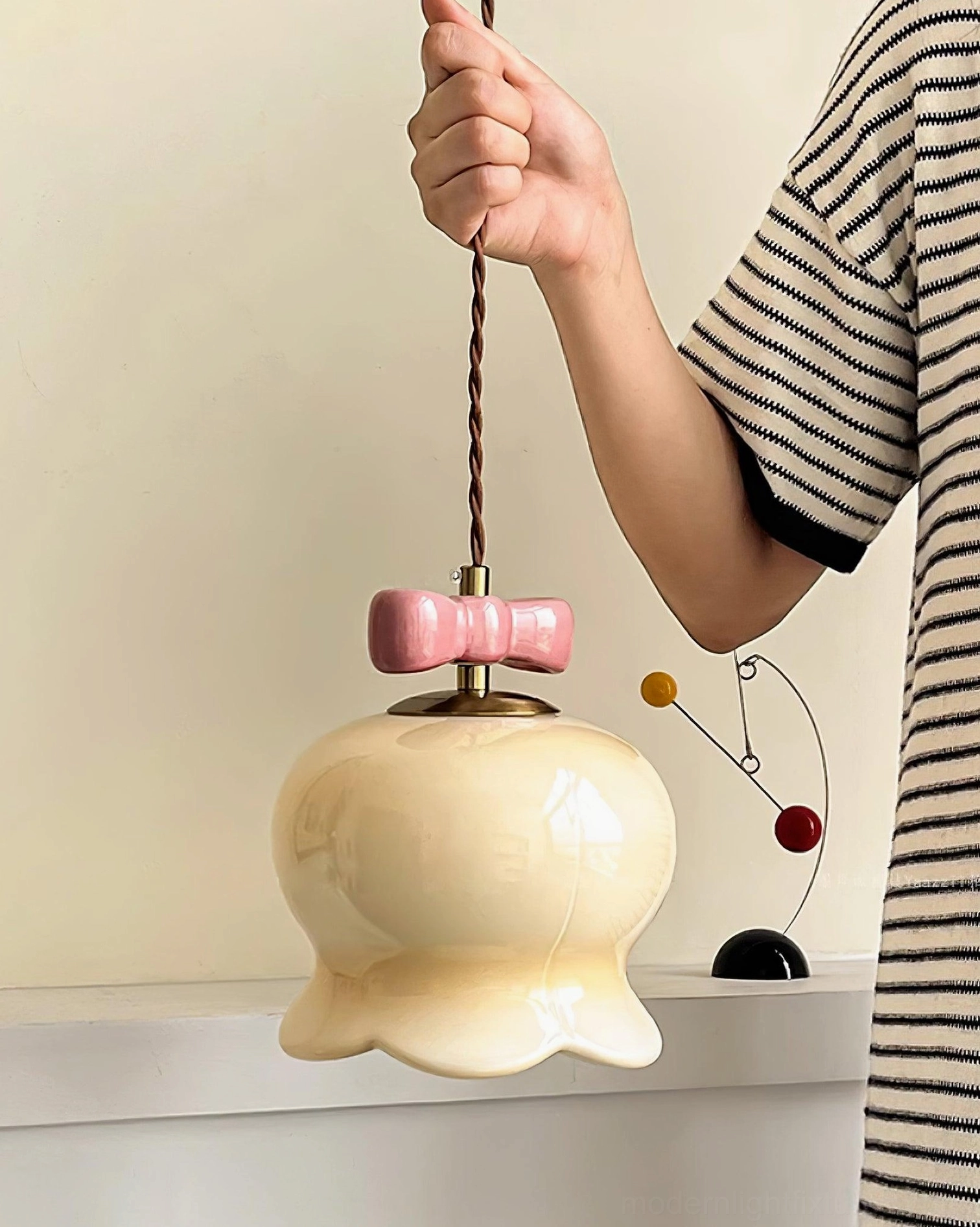 Cream ceramic pendant light showing scalloped base and glossy finish in minimalist home setting