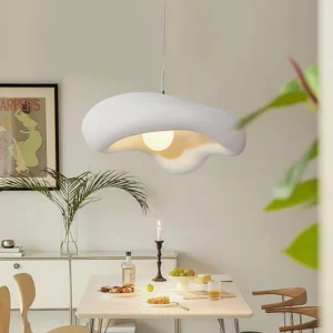 Warm cream colored cloud pendant lamp hanging in Nordic style dining room above set dinner table