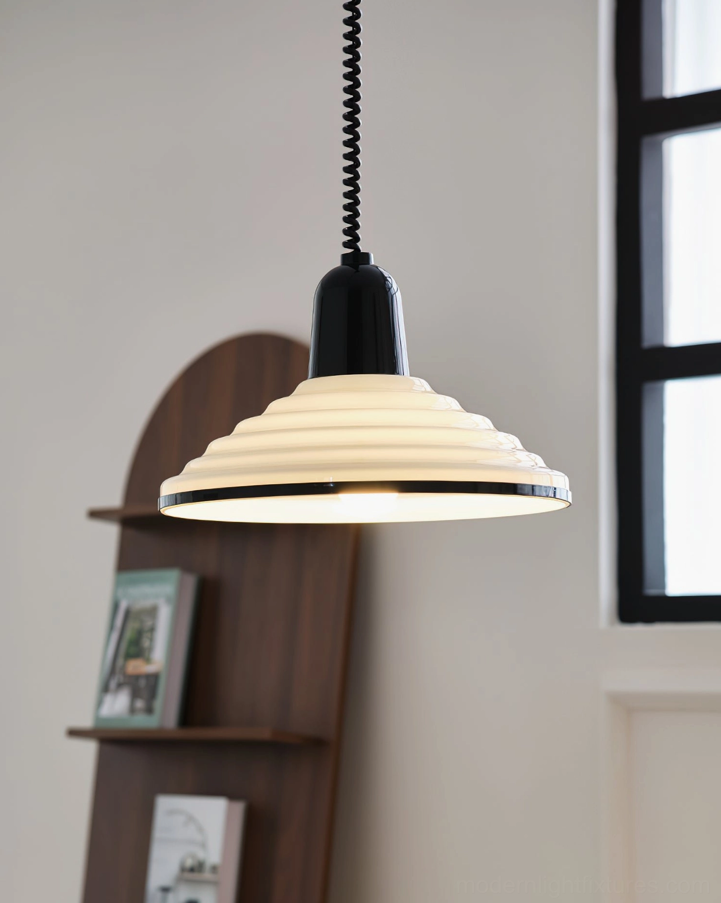 Cream ribbed pendant light with illuminated warm internal light and coiled cord, mid-century modern style residential setting