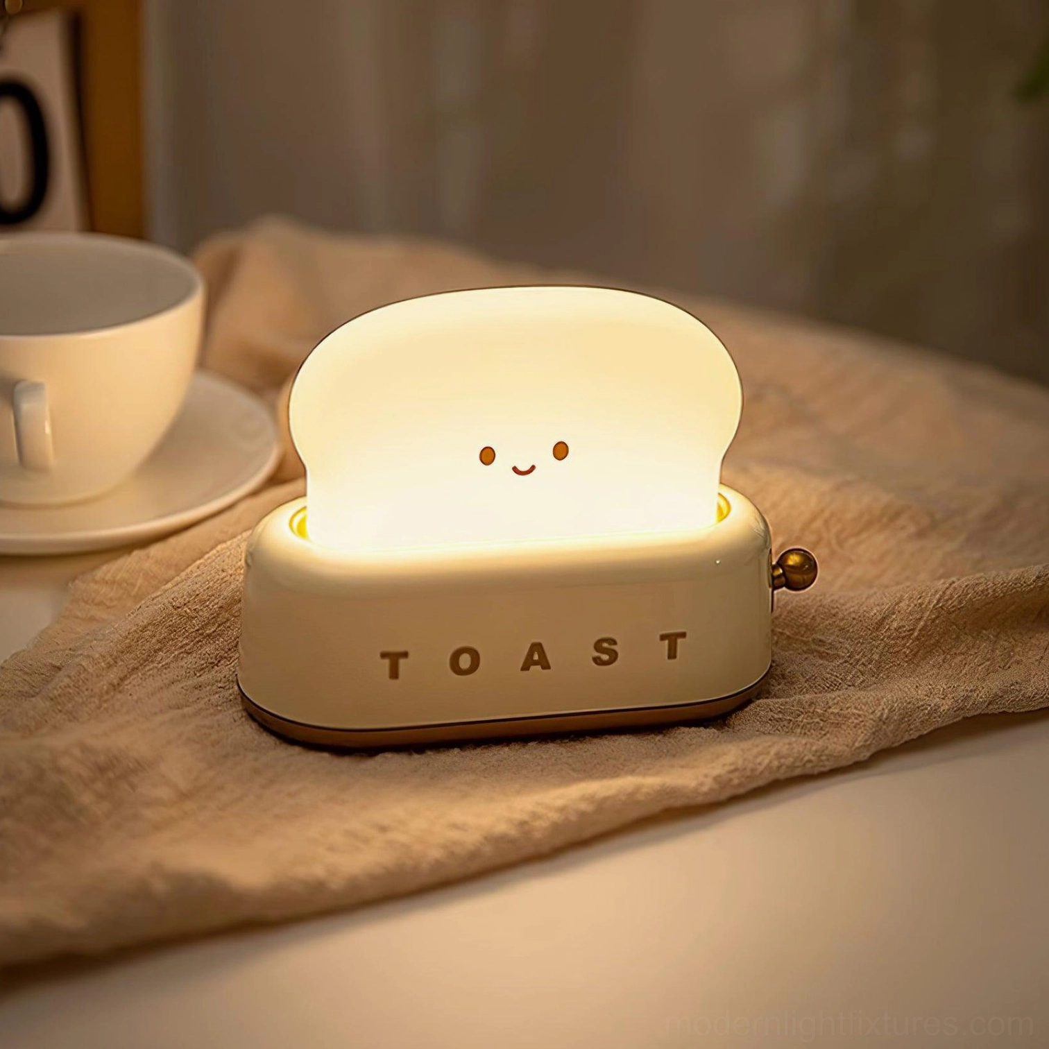 Cream and brown toaster-style table lamp on home office desk with coffee cup and linen fabric