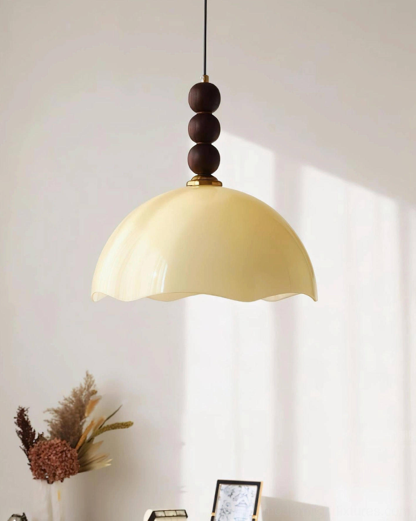 Side hanging view of creamy yellow rippled glass pendant lamp with dark wood finial against white wall backdrop