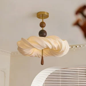 Close-up detail of Cremelle semi-flush mount fixture showing stacked walnut wood beads in light and dark tones, warm brass metal stem, and twisted cream fabric shade