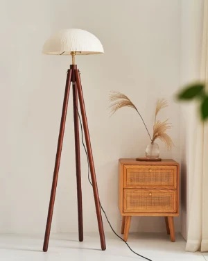 Dark walnut tripod floor lamp with white fabric shade beside bedroom side table, boho interior styling