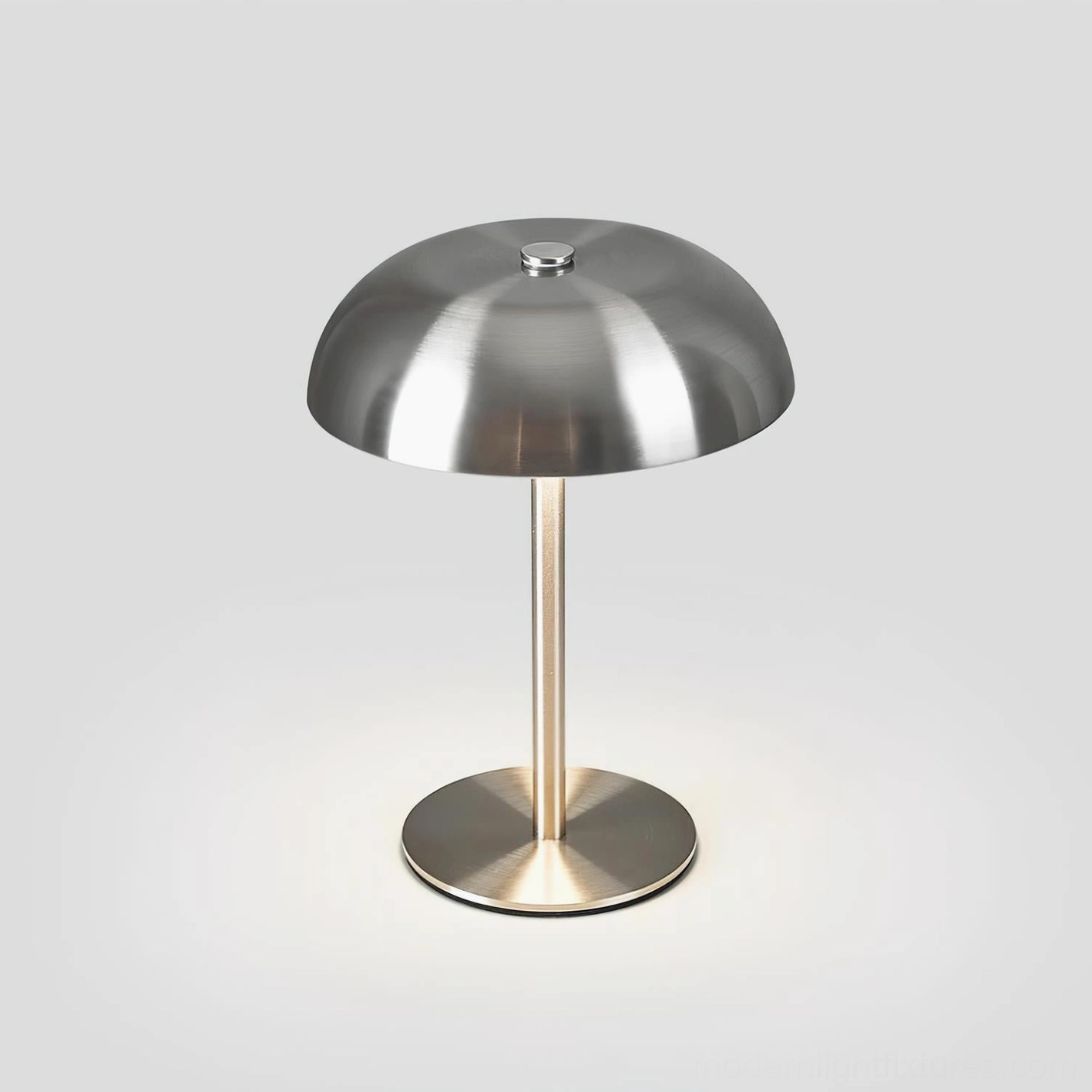 Lit Crescent metal table lamp with warm glow around brushed metal base and tapered stem
